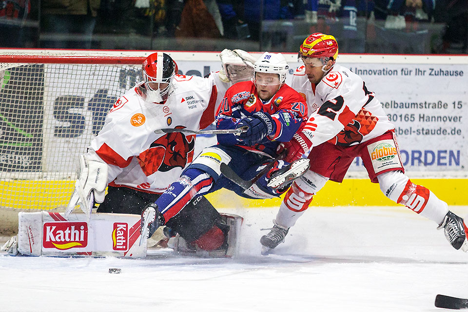 Hannovers Dennis Arnold wird von Halles Alexander Zille von den Beinen geholt. MEC-Goalie Kevin Beech behlt den Puck im Auge.