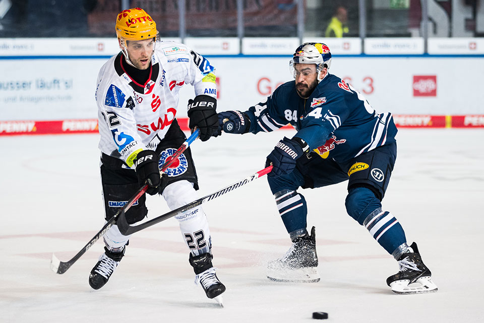 Vladimir Eminger von den Pinguins Bremerhaven spielt einen Pass vor Trevor Parkes.